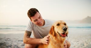 Relax, man and happy with dog at beach for loyalty, companion or travel adventure with affection. V